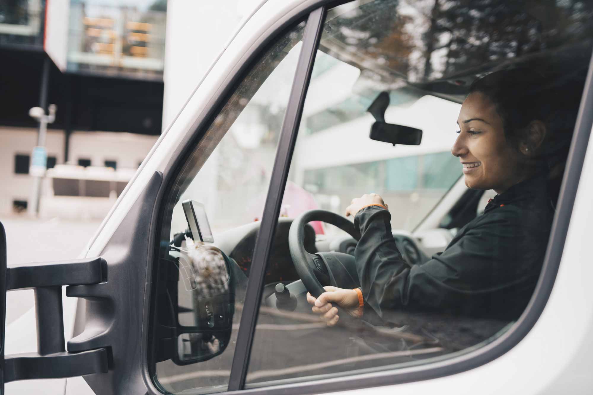 A happy woman driving a transport vehicle.