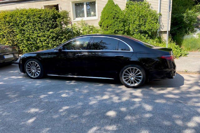 A black luxury limousine of the brand and model Mercedes Benz S.
